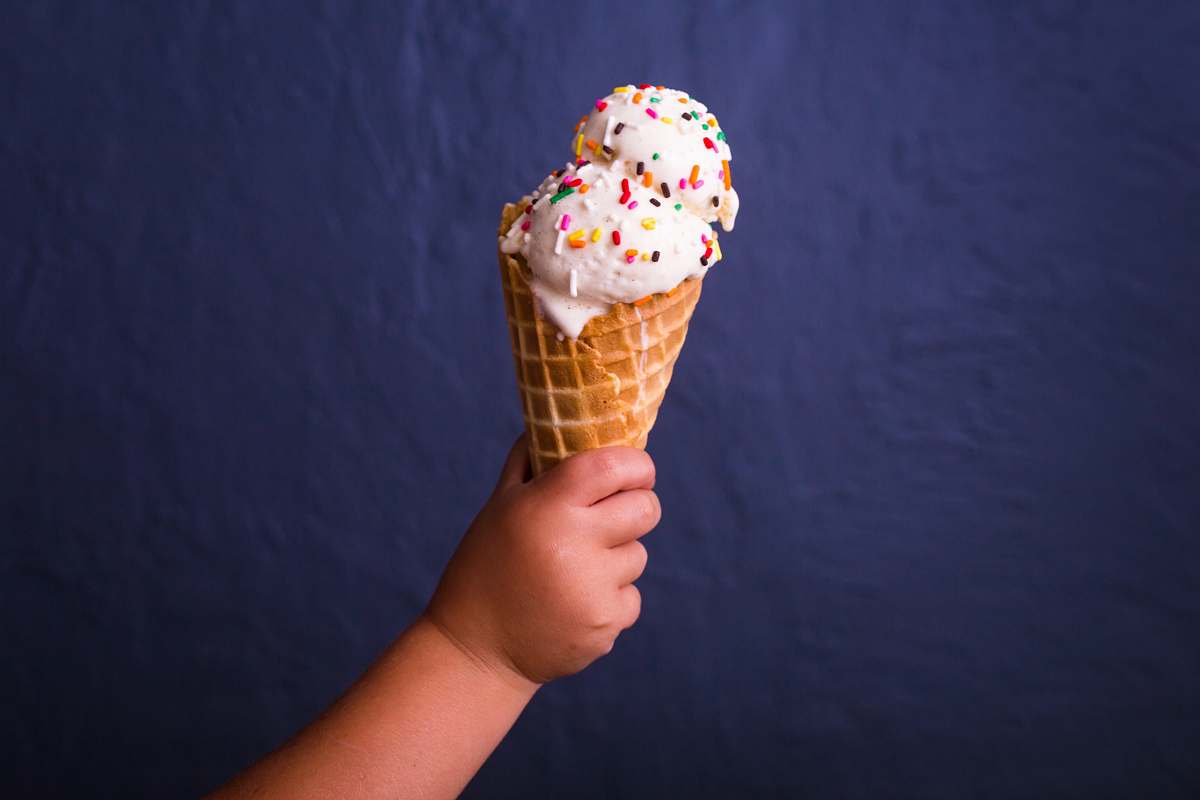 ice cream children holding brown ice cream cone with strawberry icecream cream